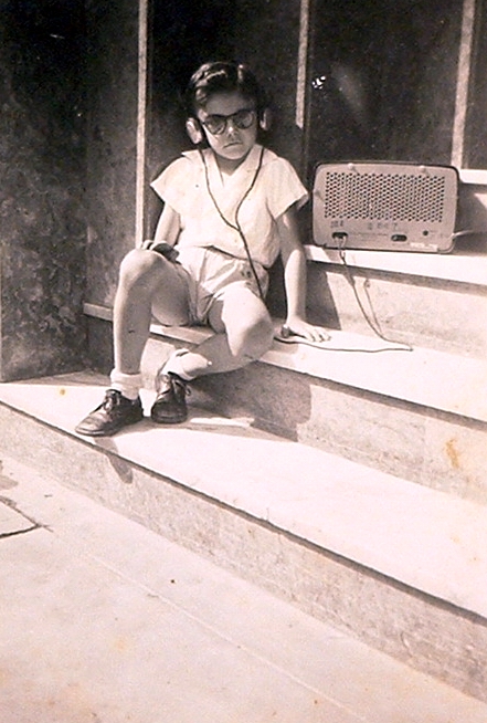 Álbum de família: este aí sou eu, na porta de casa, com óculos de sol e fones de ouvido, ouvindo rádio.